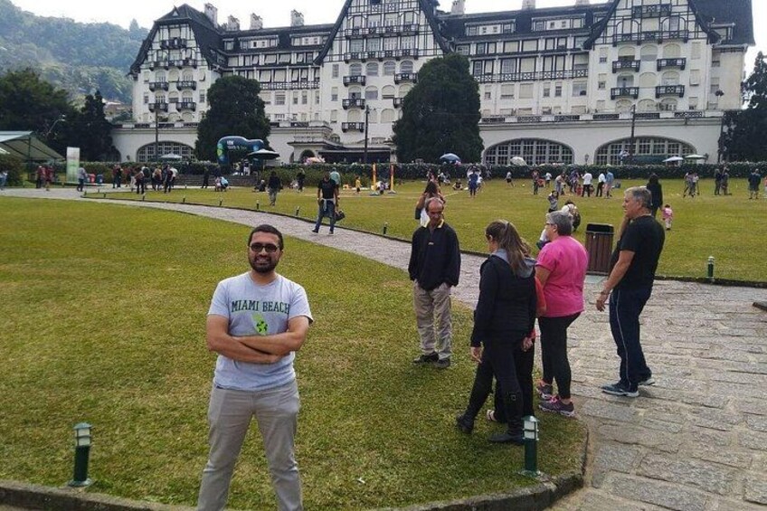 A group of people standing on grass in front of a large building with a white facade and black accents. 5