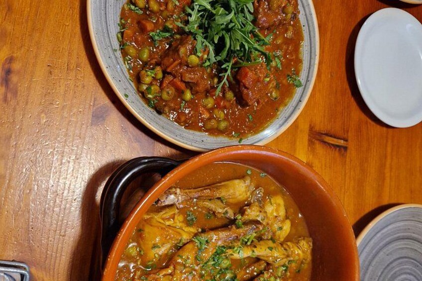 Two bowls of stew with meat and vegetables, garnished with herbs, on a wooden table. 2