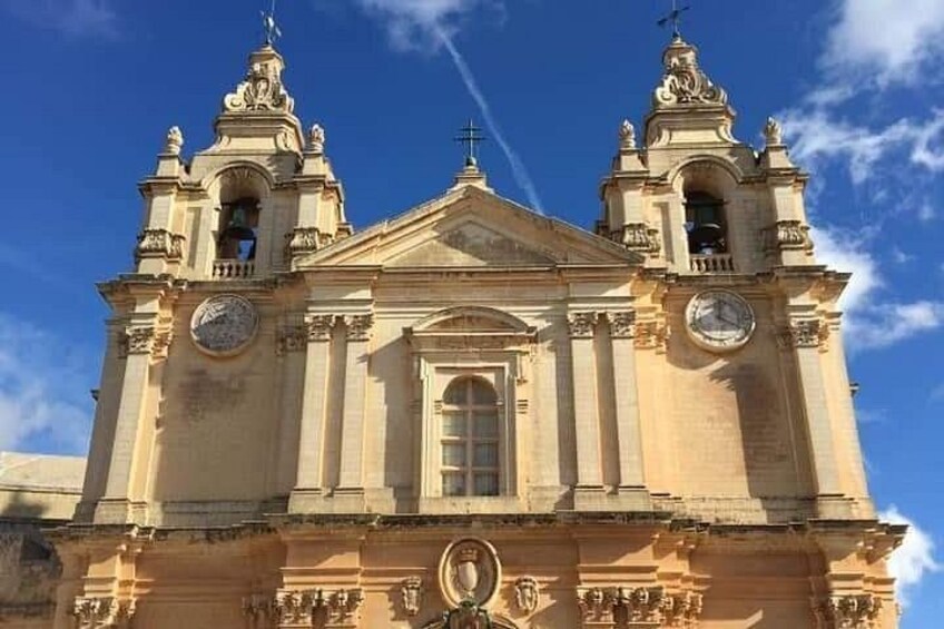 A historic church with two bell towers, a central dome, and a clock on each tower. 1