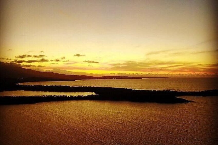 A sunset over a calm body of water with distant landforms. 2