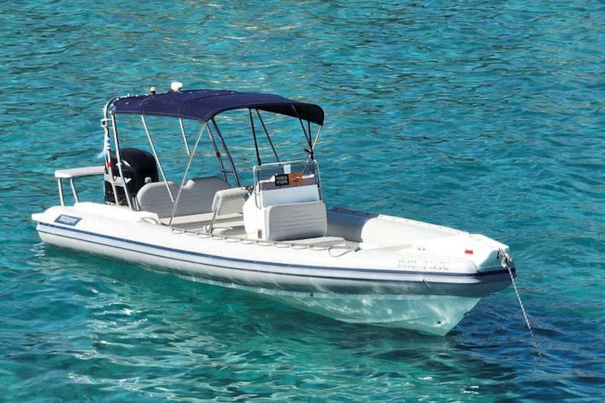 A small motorboat with a canopy, white hull, and a single outboard motor, floating on clear blue water. 4