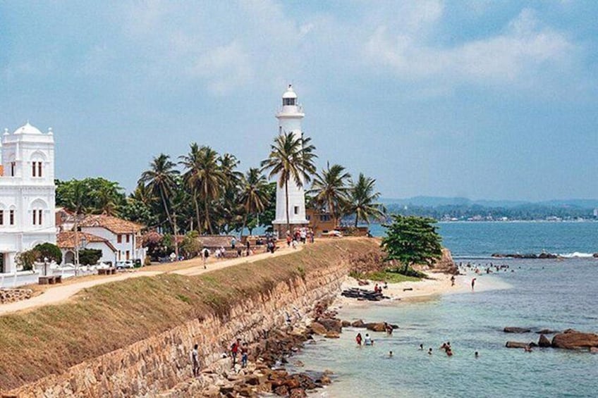 A coastal town with a lighthouse, palm trees, and a beach. 1