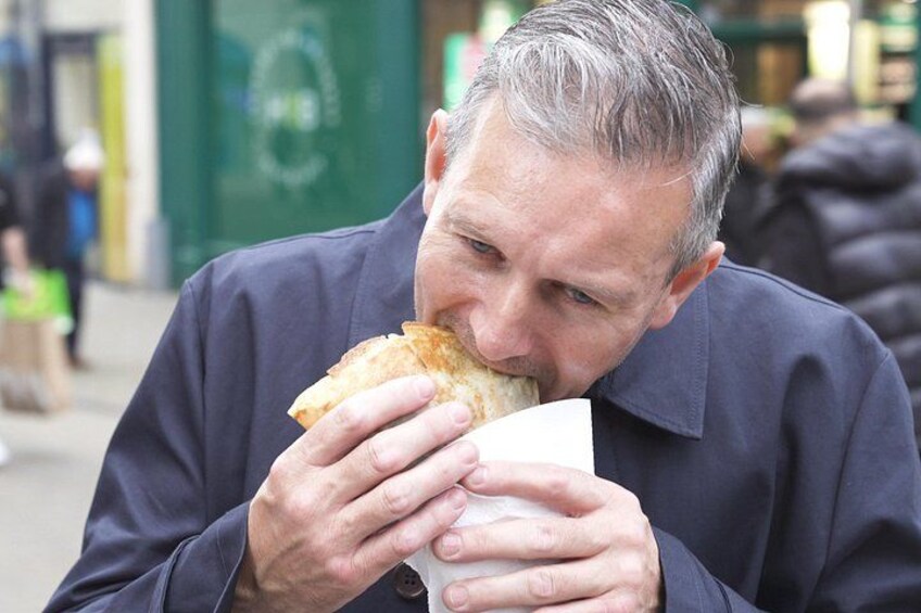 Eine Person isst ein Sandwich draußen. 4