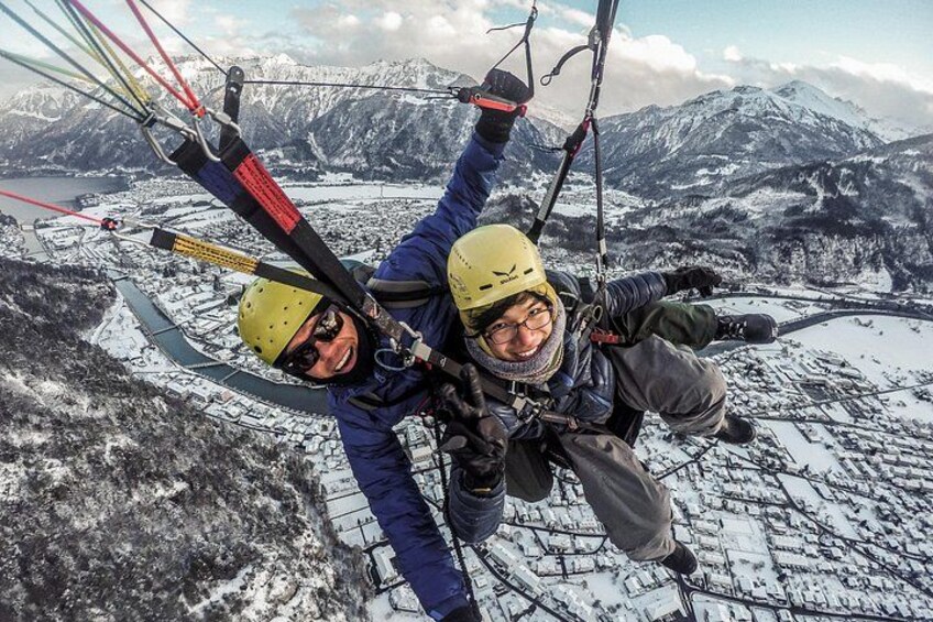 Two people paragliding over a snowy landscape with mountains in the background. 4