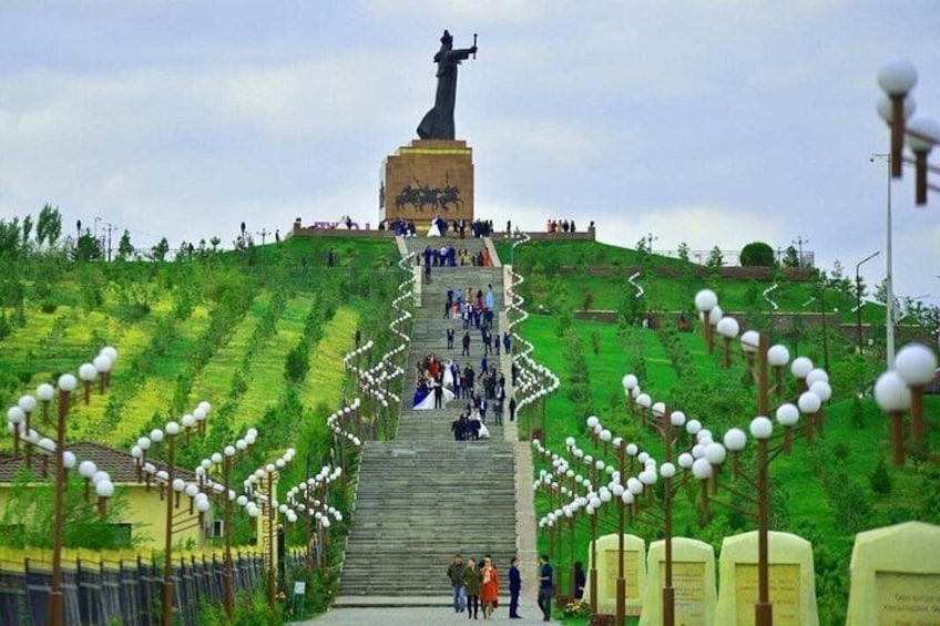 A monument with a statue at the top, surrounded by a staircase and greenery. 1