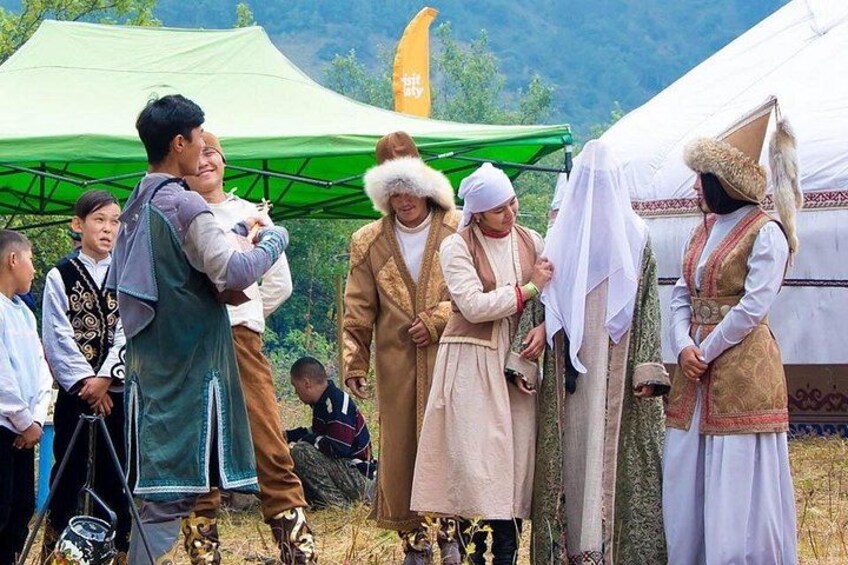 A group of people in traditional attire standing outdoors, possibly at a cultural event or festival. 1