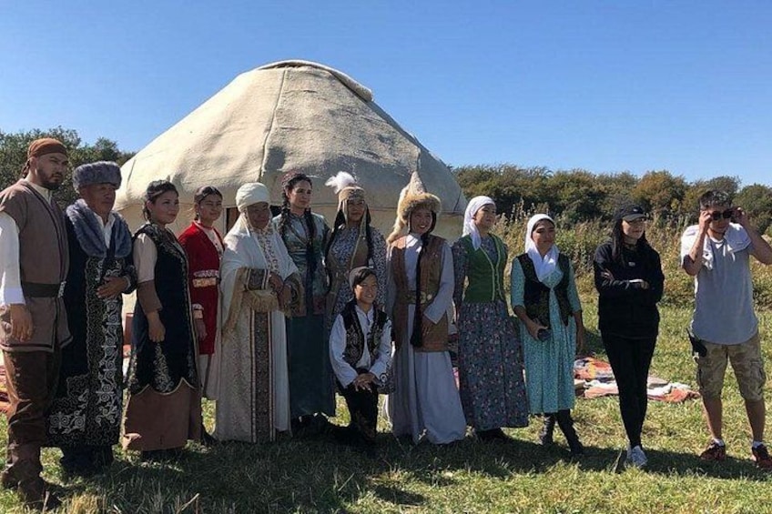 A group of people in traditional attire standing in front of a large tent-like structure in an outdoor setting. 5