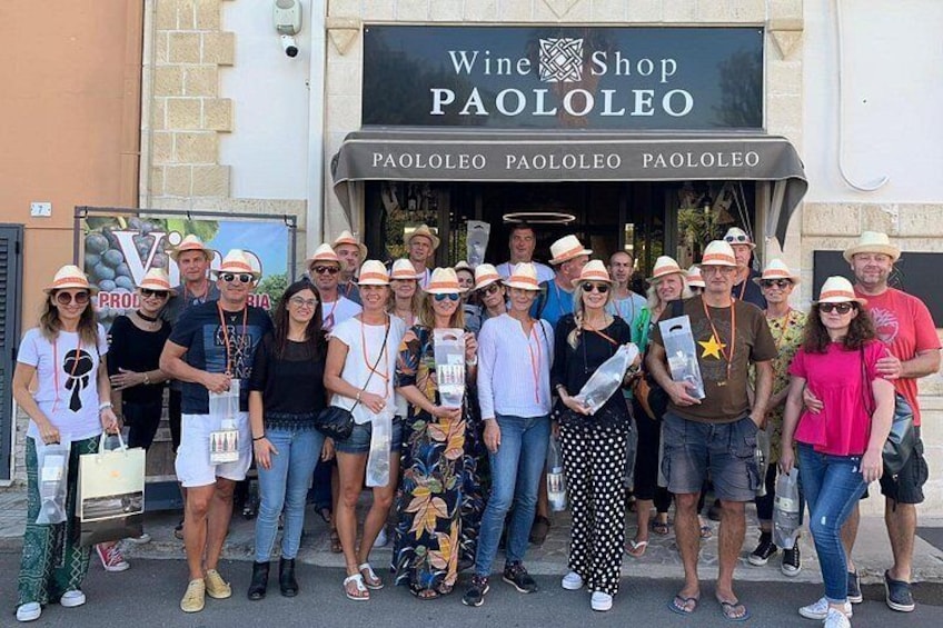 A group of people standing in front of a wine shop named 'PaoloLeo.' 5