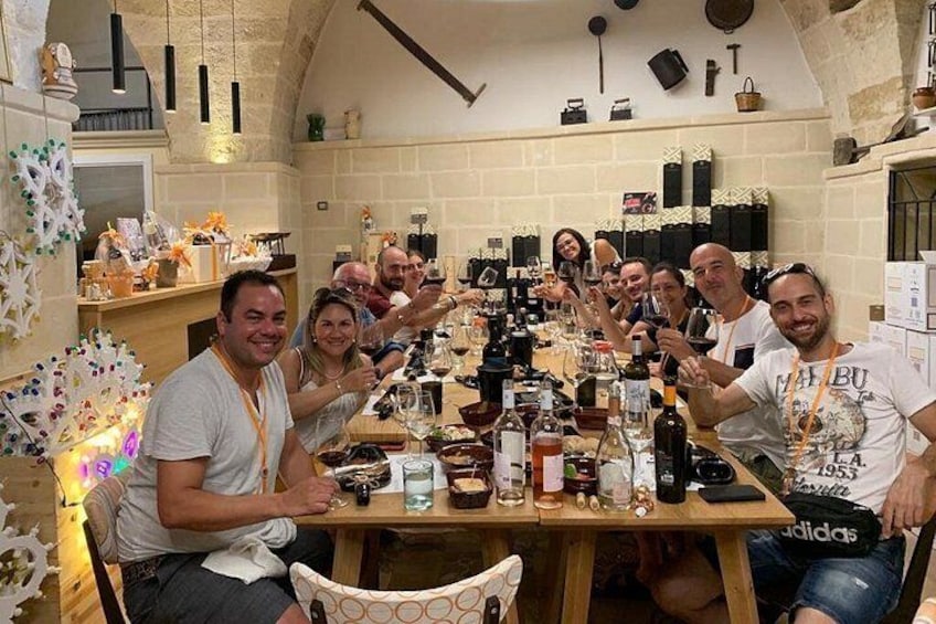 A group of people toasting at a long wooden table in a rustic kitchen setting. 4