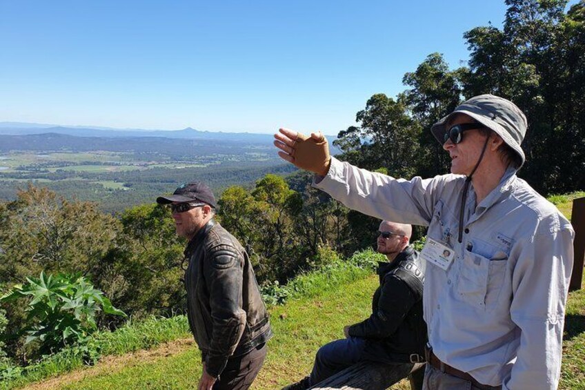 Three people on a hill overlooking a landscape with trees and distant hills. 5