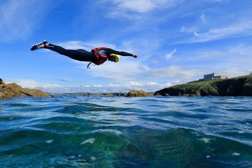 A person diving into the water with a clear sky and a building in the background. 3