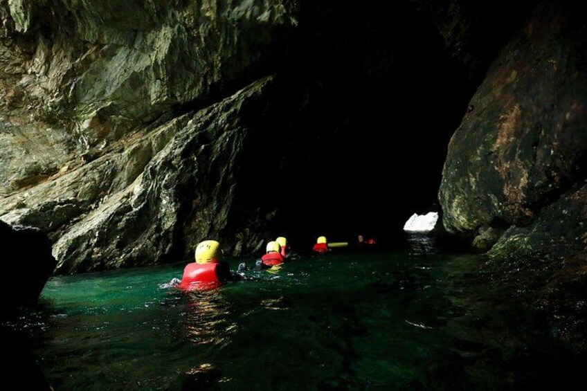 People kayaking in a cave with rocky walls and a white object in the water. 2