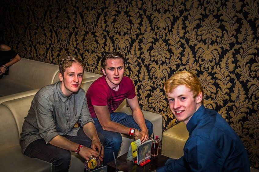 Three people sitting on a couch with a patterned wallpaper background. 4