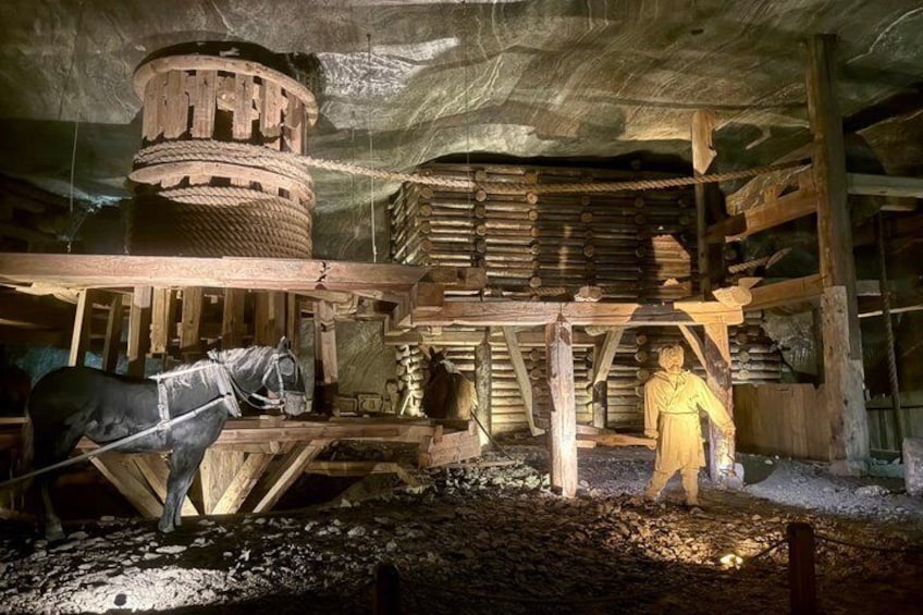 A historical mining site with wooden structures, a horse, and a miner figure. 5