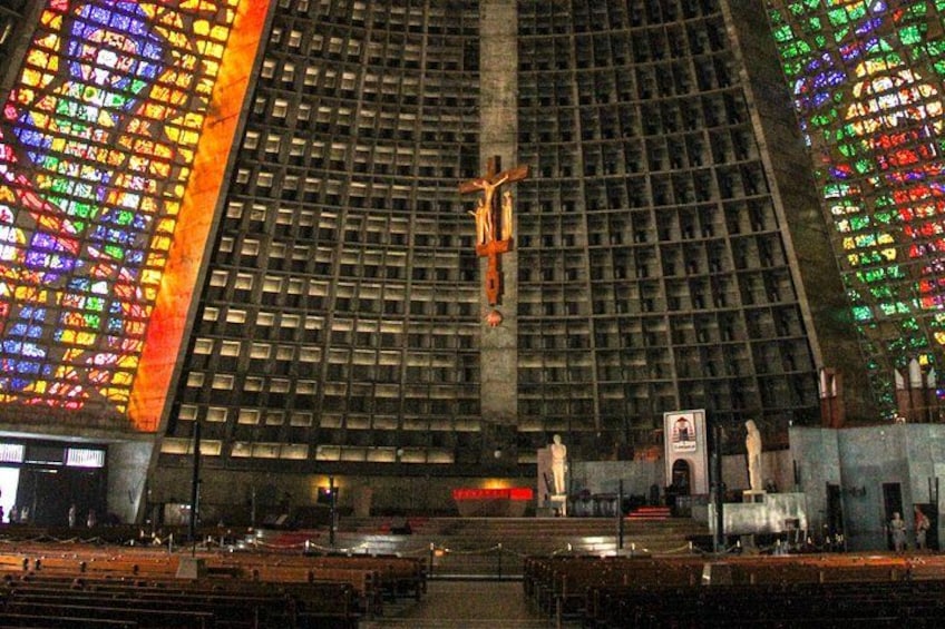 A large cathedral interior with stained glass windows, a crucifix, and statues. 4