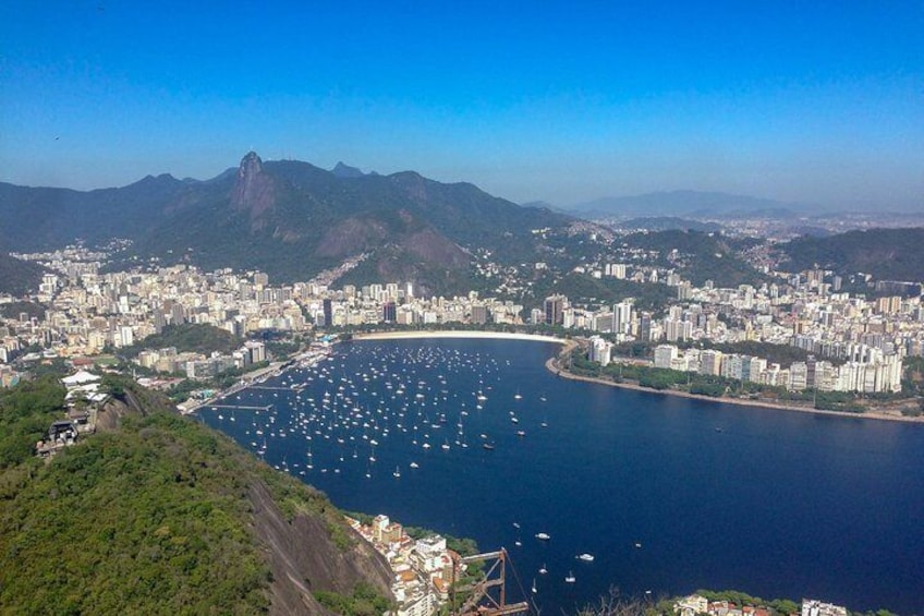 A coastal city with a bay filled with boats, surrounded by mountains and urban buildings. 3