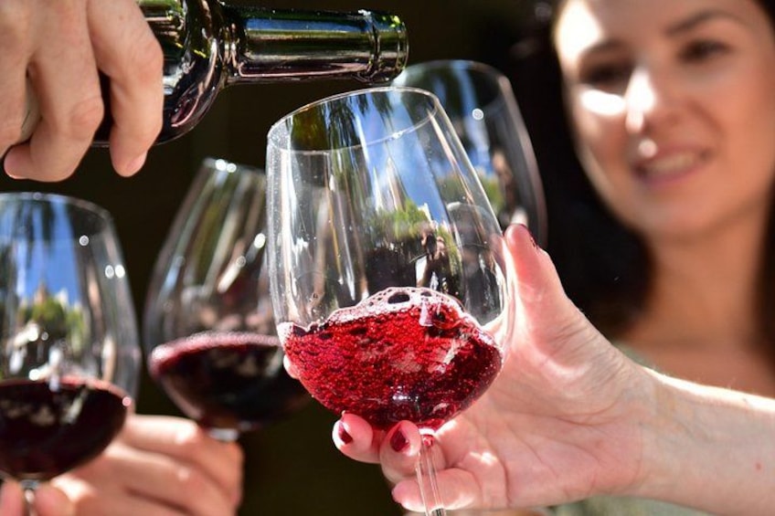 Una persona sirviendo vino tinto en una copa. 4