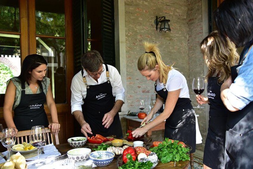 Personas preparando comida al aire libre, con una mesa llena de ingredientes y utensilios de cocina. 5