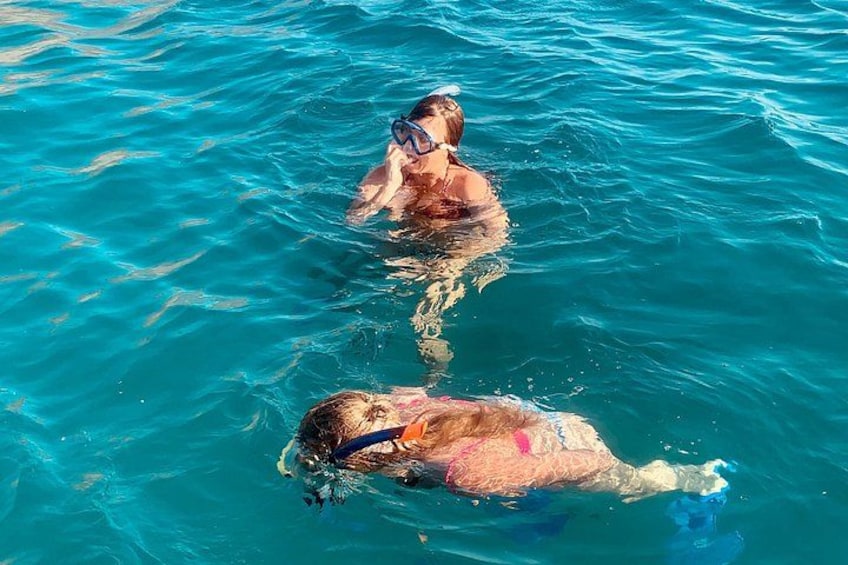 Two people swimming in clear blue water. 1