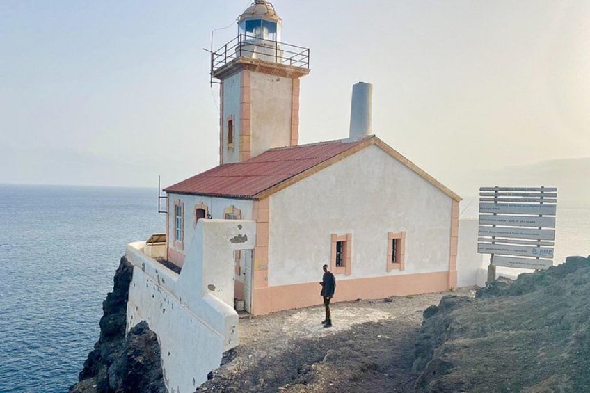 A lighthouse with a red roof, a person standing in front, and a signboard. 3