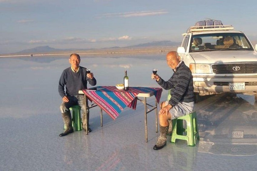 Two people sitting at a table with a vehicle in the background. 4
