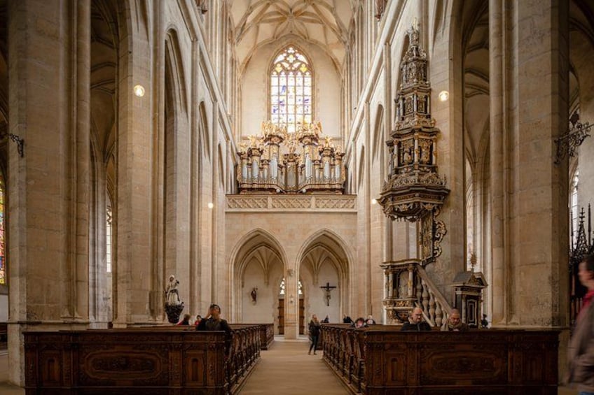 A cathedral interior with high vaulted ceilings, a large stained glass window, and ornate altars. 4