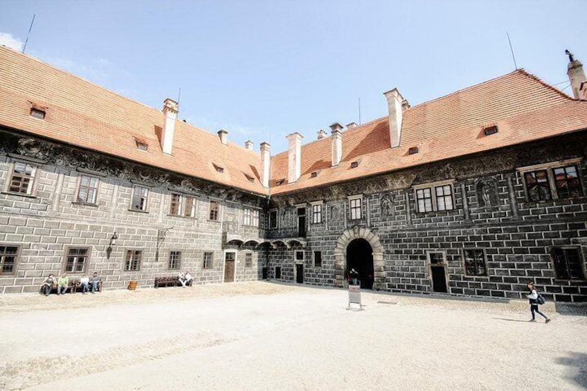 A courtyard with a stone building featuring a red-tiled roof and an arched entrance. 3
