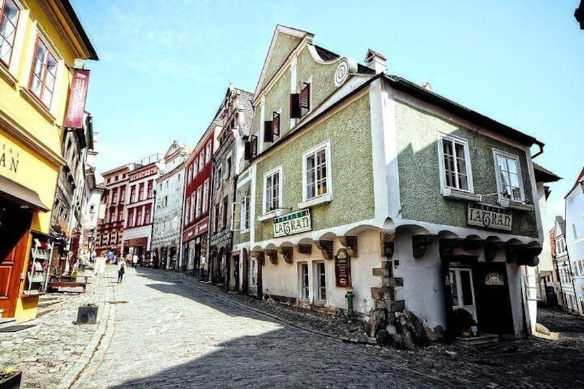 A cobblestone street lined with historic buildings, including a green building with 'LAGRAD' signage. 2