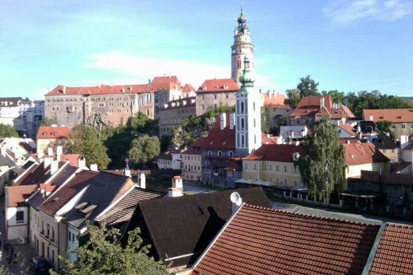 A town with historic buildings, a prominent tower, and red-tiled roofs. 5