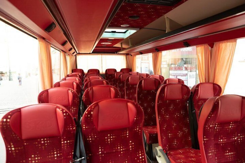 Interior de un tren con asientos rojos y ventanas. 2