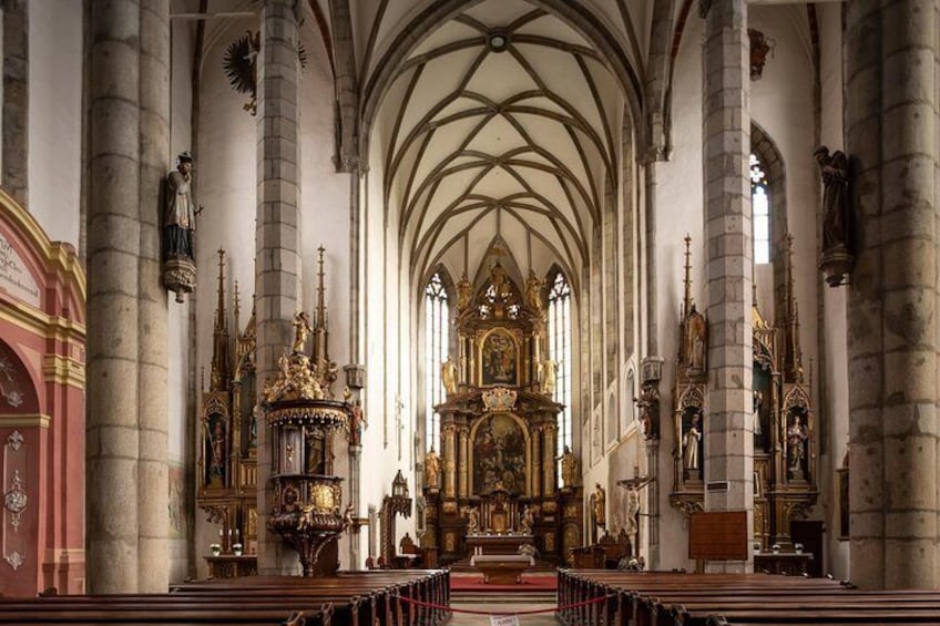 Interior de una catedral con altos techos abovedados, grandes columnas y elaboradas estatuas y altares religiosos. 5