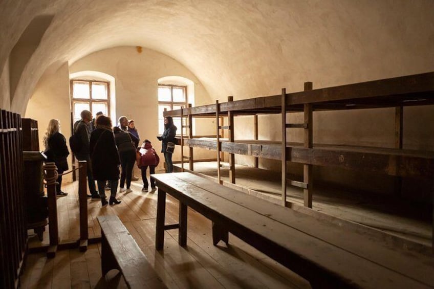 A group of people inside a building with wooden benches and a high arched ceiling. 5