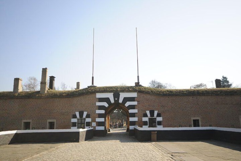 Een gebouw van baksteen met een groot hek en twee vlaggenmasten. 3