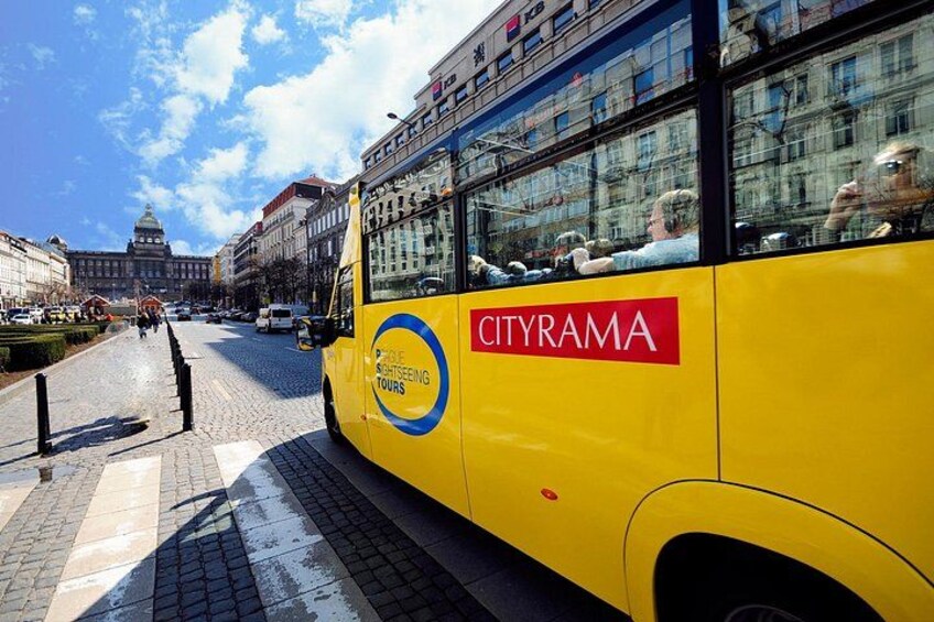A yellow Cityrama bus parked on a cobblestone street with a cityscape in the background. 4