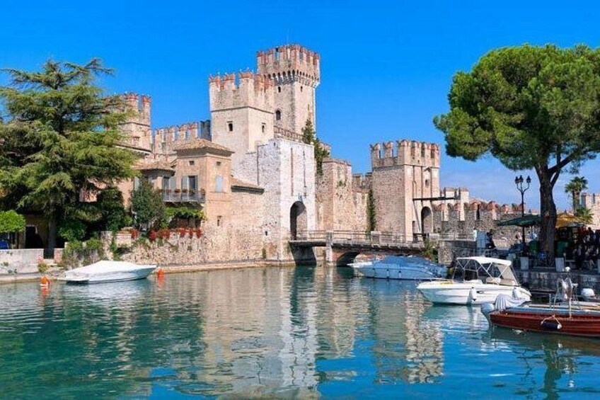 A historic castle by a calm river with boats docked nearby. 1