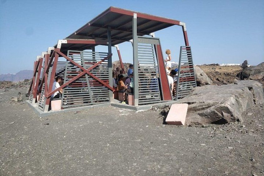 A metal shelter with a roof, surrounded by rocky terrain and a clear sky. 2