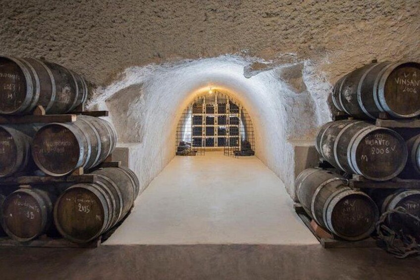 Une cave à vin souterraine avec des murs en pierre et des barriques en bois. 5