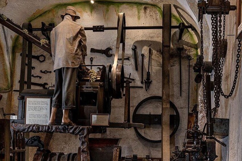 Un atelier historique où l’on peut admirer un mannequin vêtu de vêtements d’époque, entouré de machines et d’outils anciens. 2