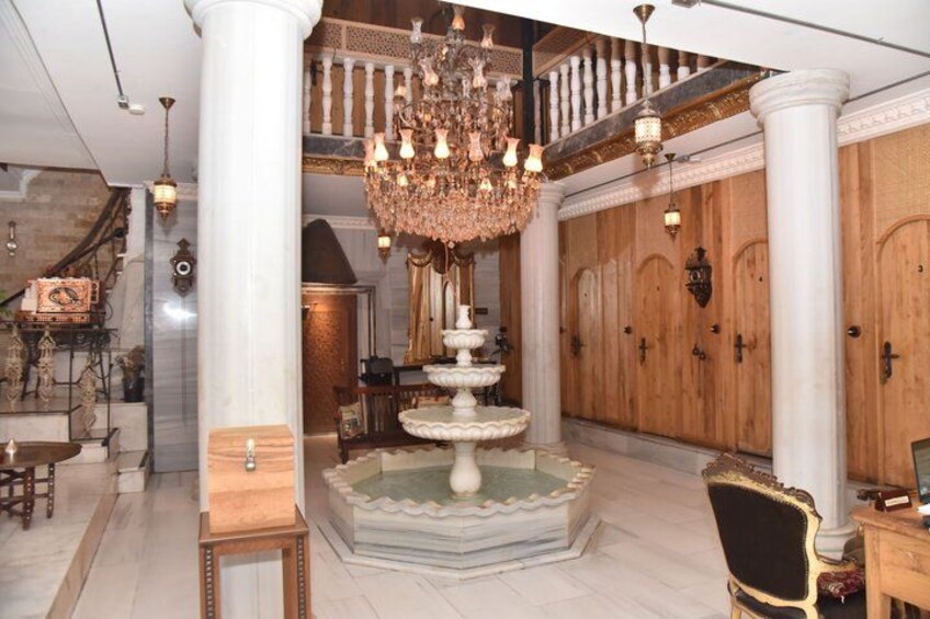 A grand foyer with a marble floor, a central fountain, and a large chandelier. 5