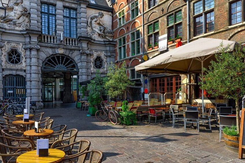 Un patio con mesas al aire libre, bicicletas y un edificio de arquitectura ornamentada. 3