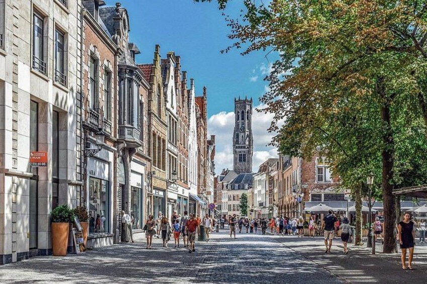A cobblestone street lined with historic buildings, a church spire, and pedestrians. 3
