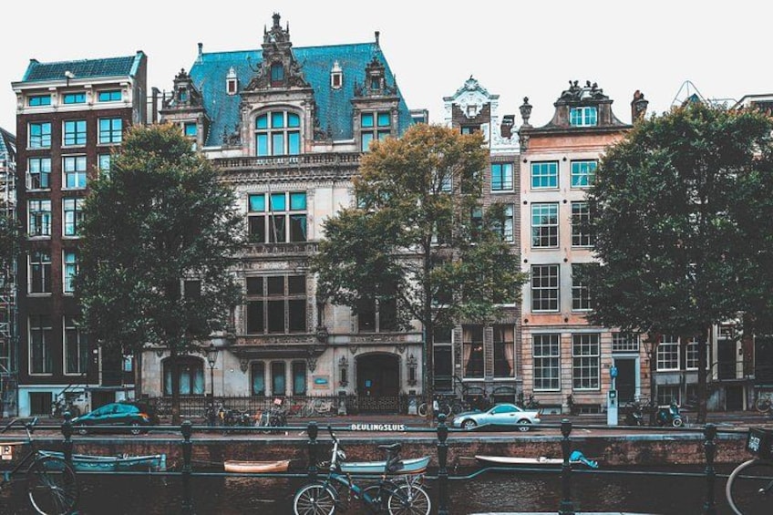 Una hilera de edificios históricos con fachadas ornamentadas, un canal con barcos y una bicicleta en primer plano. 2