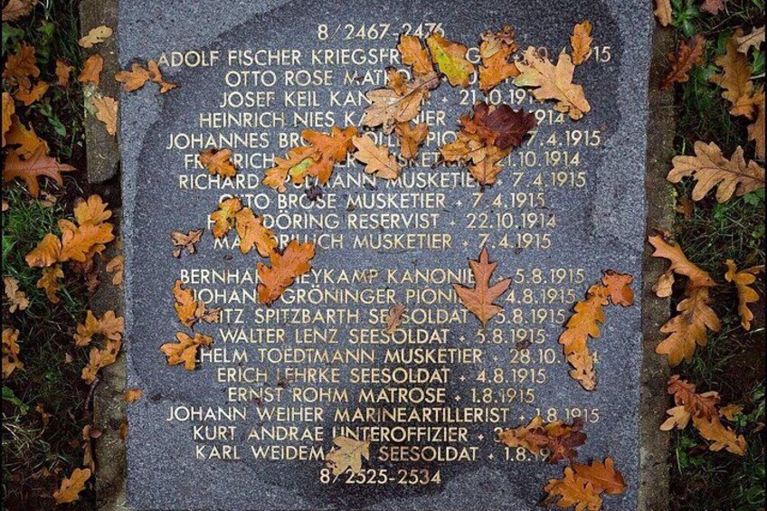 A memorial stone with names and dates, surrounded by autumn leaves. 3