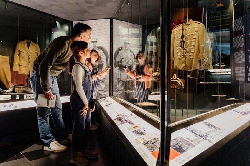 A museum exhibit with mannequins dressed in historical military uniforms, informational displays, and visitors observing the exhibits. 2