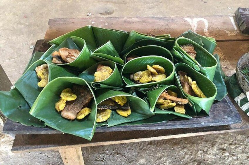 A wooden table with food items wrapped in green leaves. 4