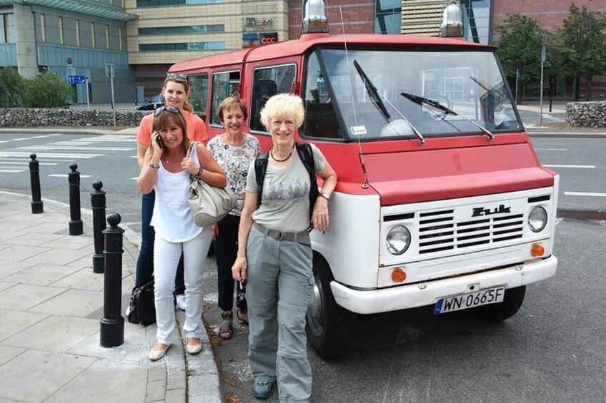 Un grupo de personas de pie junto a un autobús rojo y blanco con una placa de matrícula. 5