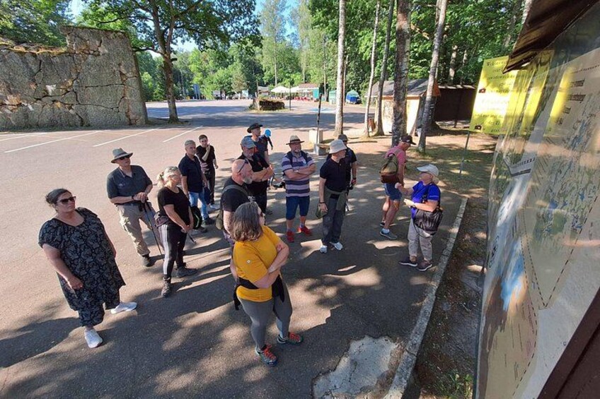 A group of people standing on a paved area with trees and a stone wall in the background. 5