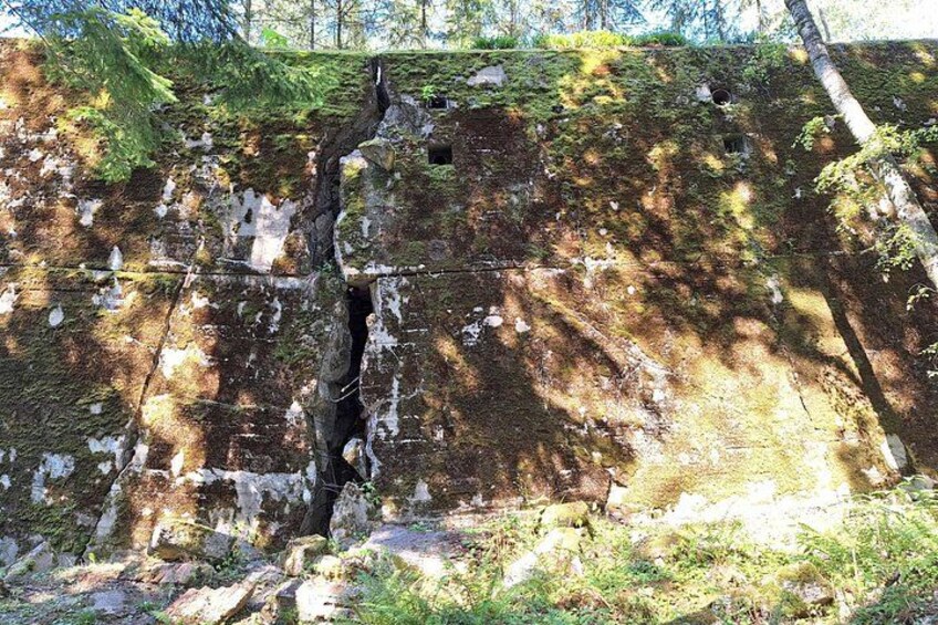 A moss-covered stone wall with a narrow passageway and a small opening. 2