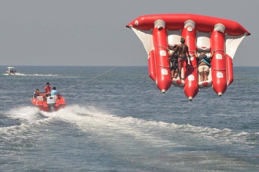 A person riding a jet ski and a person in a red and white parachute-like device over the water. 1