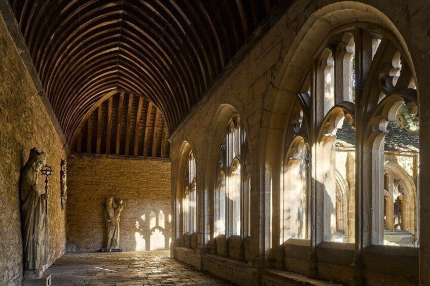 A medieval cloister with stone arches and a vaulted ceiling. 5